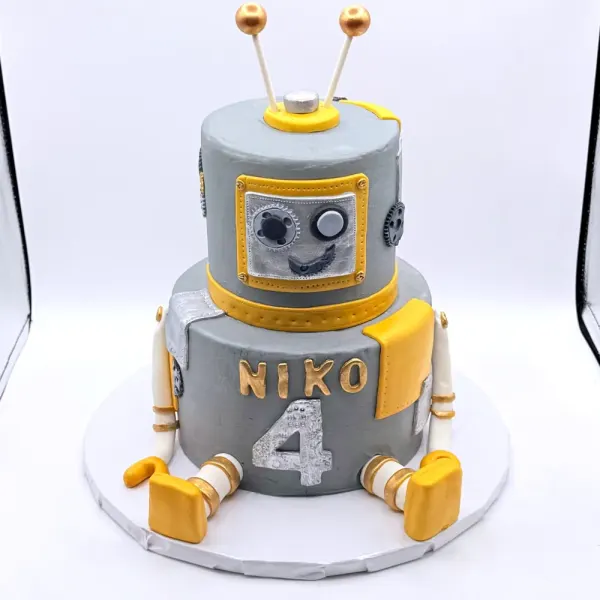 Two tier grey robot cake with gold antennae, hands and feet, lettered Niko with a number four