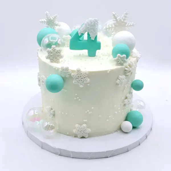 White cake with fondant snowflakes, mint and white spheres and a mint number four