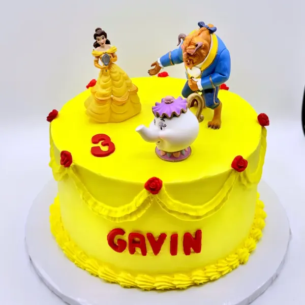 Yellow cake with Belle and Beast figures, a teapot, red roses and Gavin lettered in red