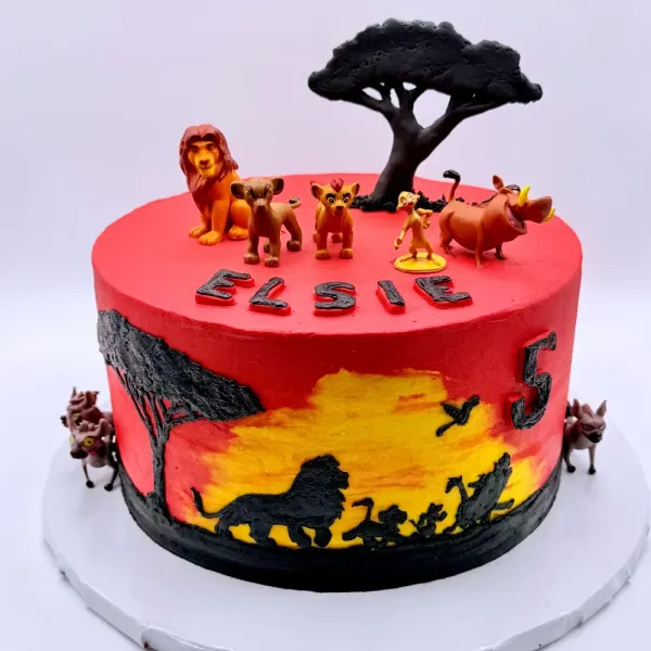 Red cake with a painted savanna silhouette, an acacia tree topper, lion figures and Elsie lettered