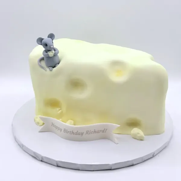 Sculpted cake shaped as a wedge of cheese with holes and two grey fondant mice on top