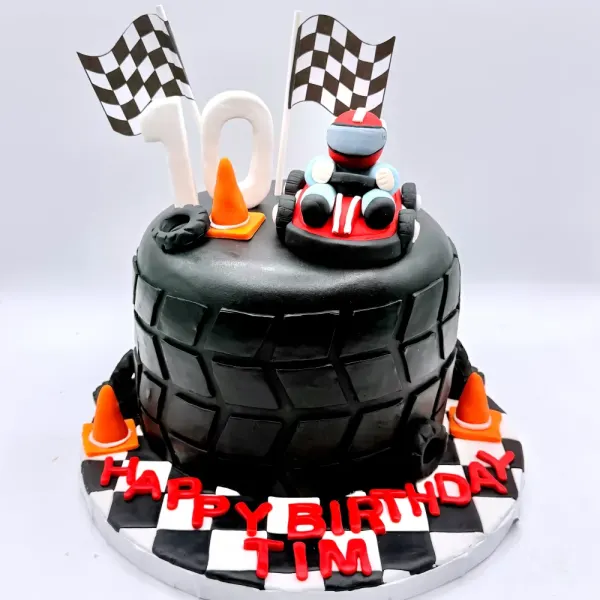 Black tire shaped cake with checkered flags, traffic cones, a race car figure and a number ten