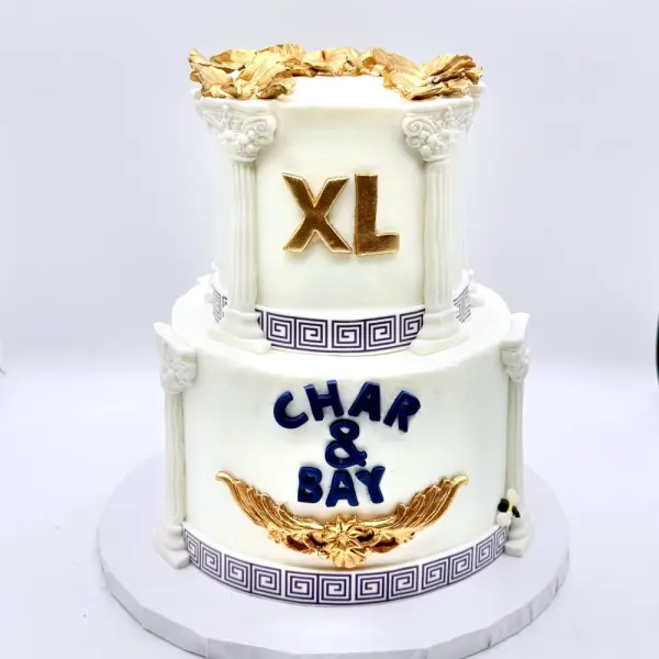 Two tier white cake with fondant columns, a Greek key border, gold laurel and XL in gold