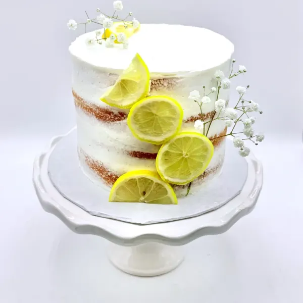 Semi naked cake with lemon slices down one side and sprigs of baby's breath