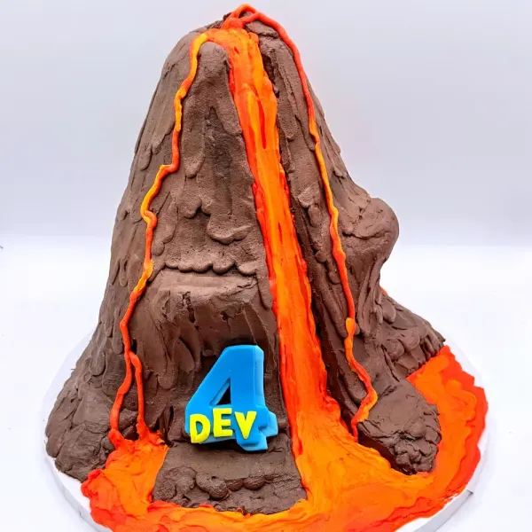 Sculpted volcano cake in brown with orange lava flows, a blue number four and a Dev plaque