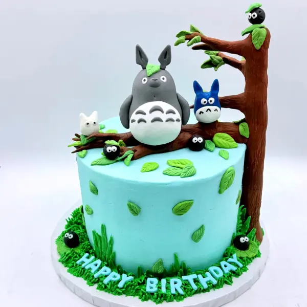 Turquoise cake with grey forest spirit figures on a fondant tree branch, leaves and a grass base