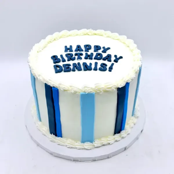 White cake with blue and navy vertical stripes and Happy Birthday Dennis piped on top