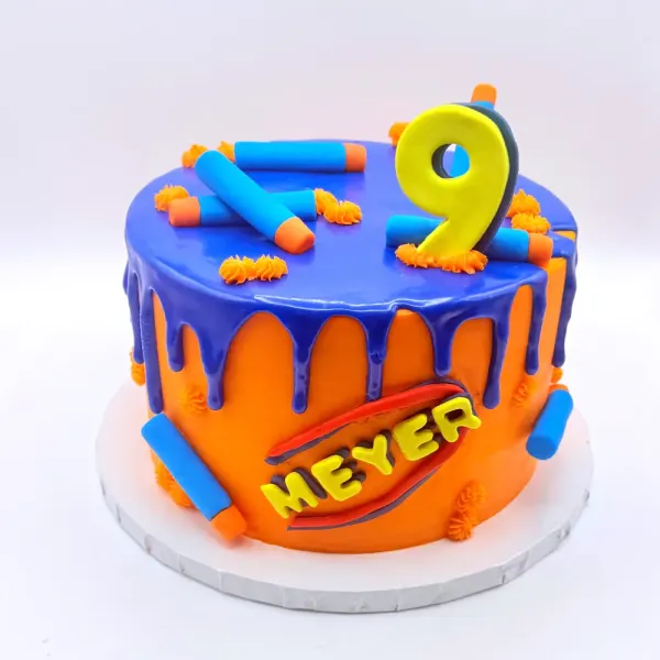 Blue and orange drip cake with foam dart shapes, lettered Meyer with a yellow number nine