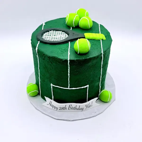 Dark green cake marked as a tennis court with a fondant racket on top and tennis balls