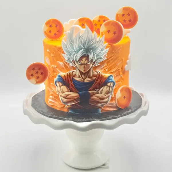 A round cake with textured orange buttercream featuring a printed image of a silver-haired anime warrior with crossed arms, surrounded by edible orange star-marked spheres and white buttercream clouds, displayed on a white ruffled cake stand.