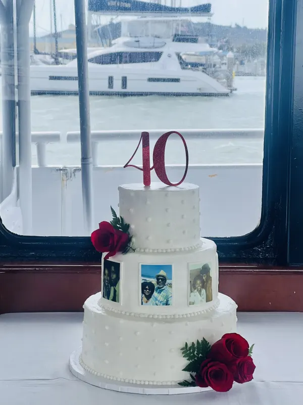 Three-tier white cake with edible photo panels, dotted piping, red roses and a red glitter 40 topper