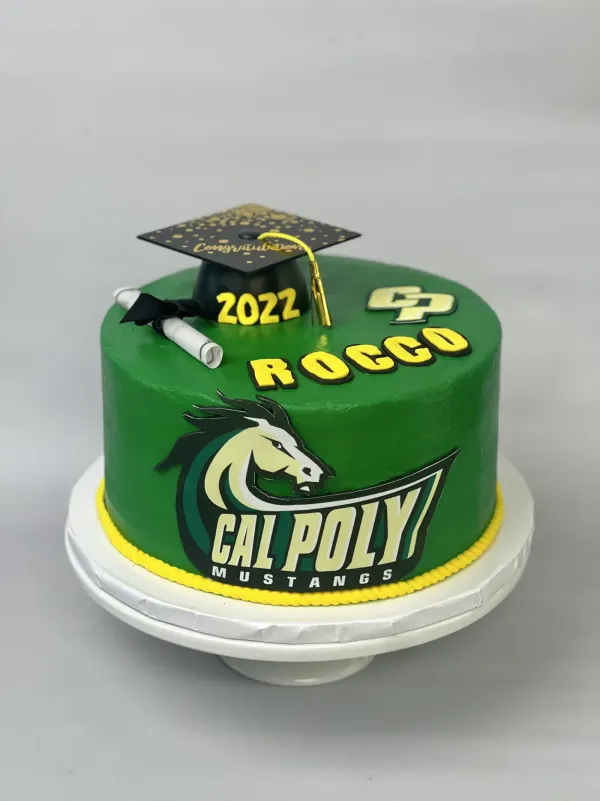 Green round cake with the Cal Poly Mustangs logo, ROCCO and 2022, a graduation cap and diploma