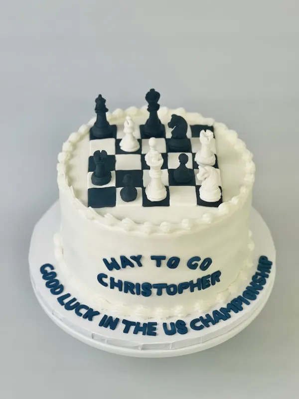 White cake with a fondant chessboard and pieces reading Way To Go Christopher and Good Luck