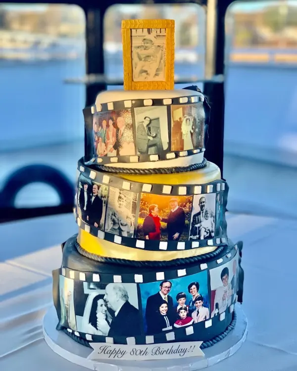 Three-tier cake wrapped in a fondant film strip of edible family photos with a Happy 80th banner