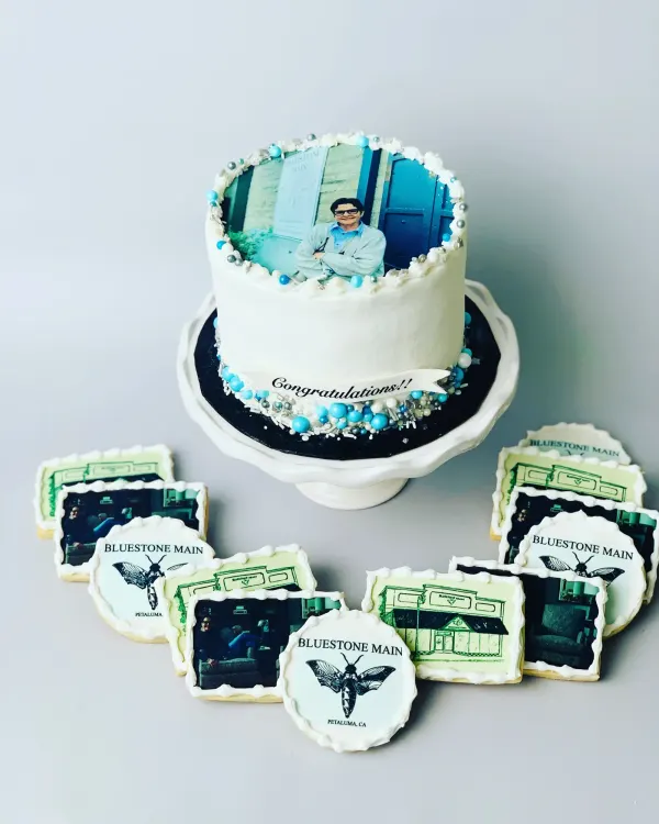 White cake with an edible photo print and Congratulations banner, with Bluestone Main logo cookies