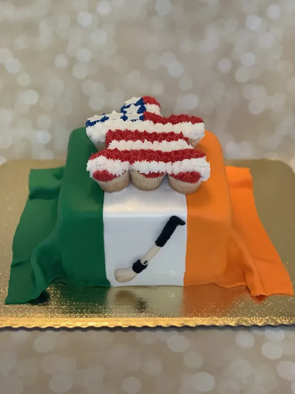 Square cake iced as the Irish flag with a fondant hurling stick, topped by star-shaped US flag cupcakes