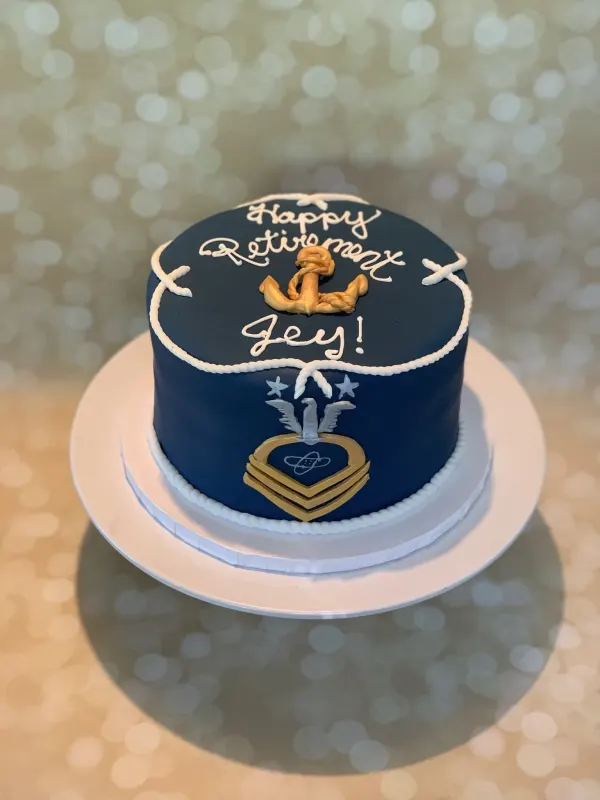 Navy round cake piped Happy Retirement Jey with a gold anchor, rope border and chief insignia