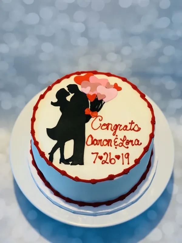 Light blue cake with a black couple silhouette and heart balloons, piped Congrats Aaron and Lora