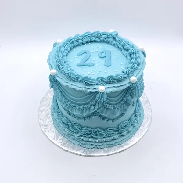 Blue vintage piped cake with ruffles, swagged draping, pearl accents and 29 piped on top