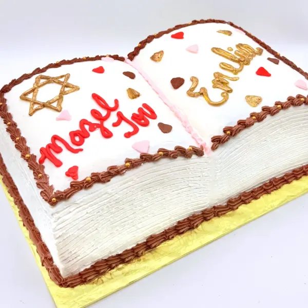 Open book shaped cake with a gold Star of David, red and gold script lettering and scattered hearts