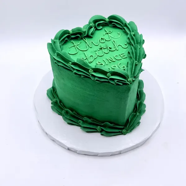Green heart shaped cake with ruffled buttercream edges and piped script lettering on top