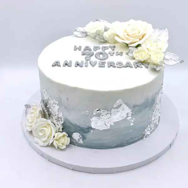 Gray and white cake with silver leaf, white sugar roses and 70th anniversary lettering in silver