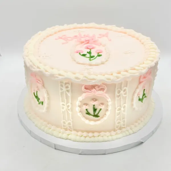Ivory vintage piped cake with pink bows, oval frames and small green sprigs