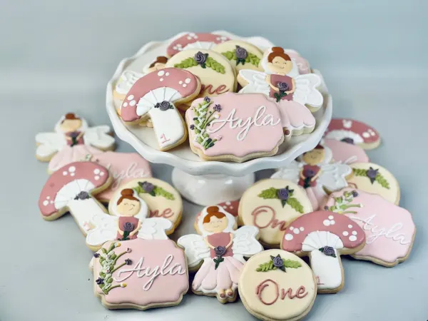 Fairy and mushroom cookies iced in dusty pink and cream, lettered Ayla and One