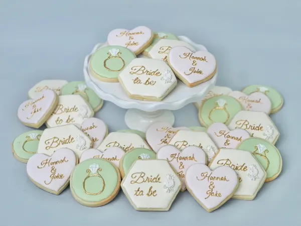 Mint and ivory bridal cookies lettered Bride to be and Hannah and Jake with gold ring rounds