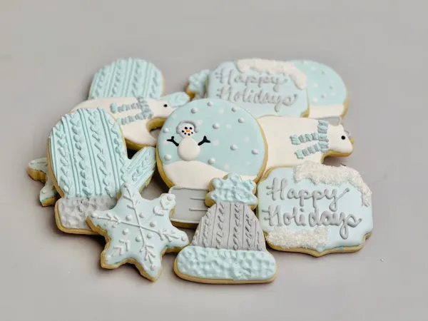 Pale blue winter cookies with a snow globe snowman, polar bears, snowflake and Happy Holidays