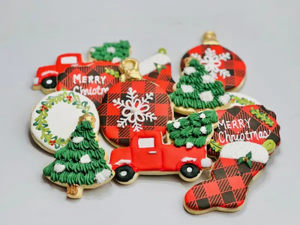 Christmas cookies in buffalo plaid with a red truck, piped trees, stocking and Merry Christmas