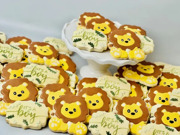 Baby shower cookies with yellow lion faces and green It's a Boy plaques with leaf detail