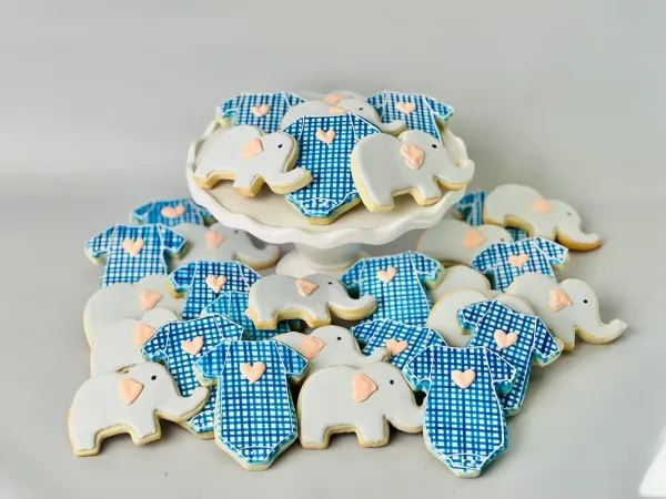 Baby shower cookies with blue gingham onesies and grey elephants with peach heart ears
