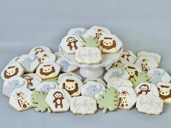 Neutral safari baby shower cookies with lion, elephant, giraffe, monkey and baby plaques