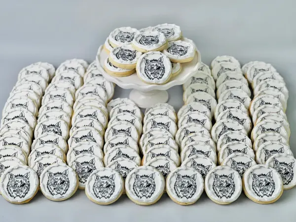 Rows of round cookies printed with the Marin Academy Performing Arts lynx logo in black