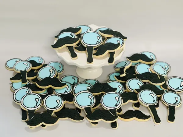 Set of black mustache cookies paired with pale blue magnifying glass cookies