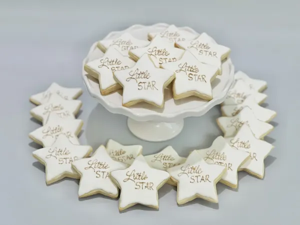White star cookies lettered Little Star in gold on a scalloped cake stand