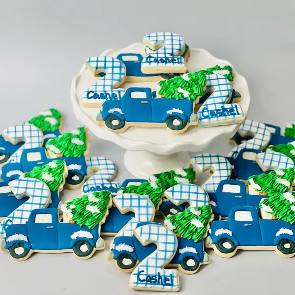 Blue truck cookies carrying green trees, with plaid number 2 and Cashel name plaques