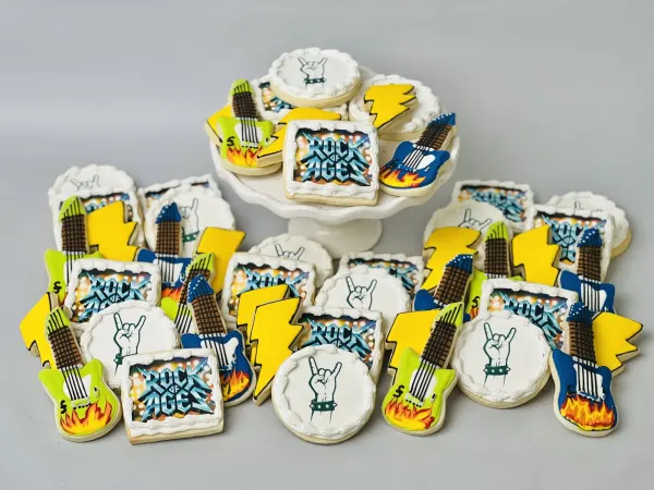 Rock of Ages cookie set with logo squares, flaming guitars, lightning bolts and rock-hand rounds