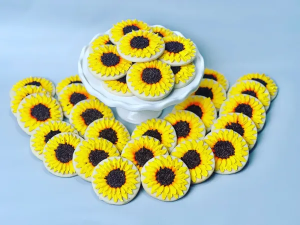 Round cookies piped with yellow buttercream sunflowers and chocolate sprinkle centers