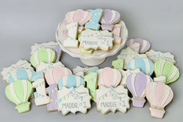 Pastel hot air balloon cookies with number 1 and plaques reading Dream Big Maddie is 1