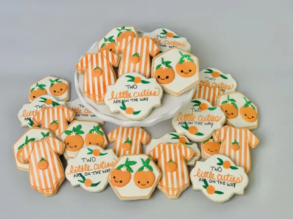 Citrus cookie set reading Two Little Cuties Are On The Way with striped onesies and smiling oranges