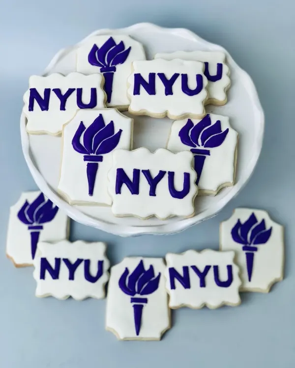 White plaque cookies iced with the purple NYU wordmark and torch logo