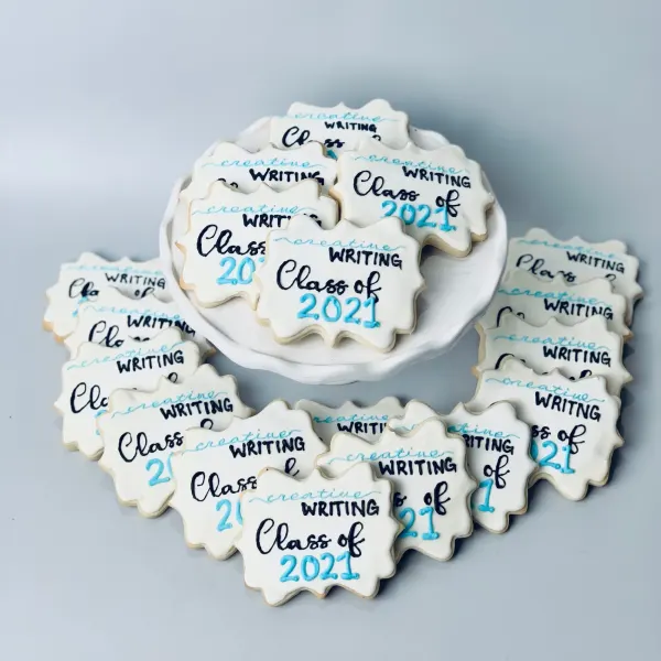 White plaque cookies hand-lettered Creative Writing Class of 2021 in black and blue
