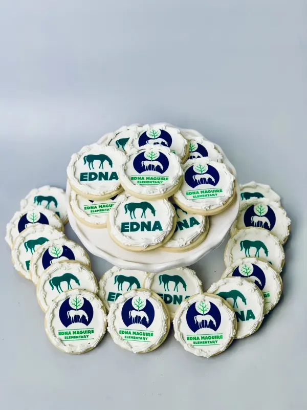 Round white cookies with printed Edna Maguire Elementary horse logos in green and navy
