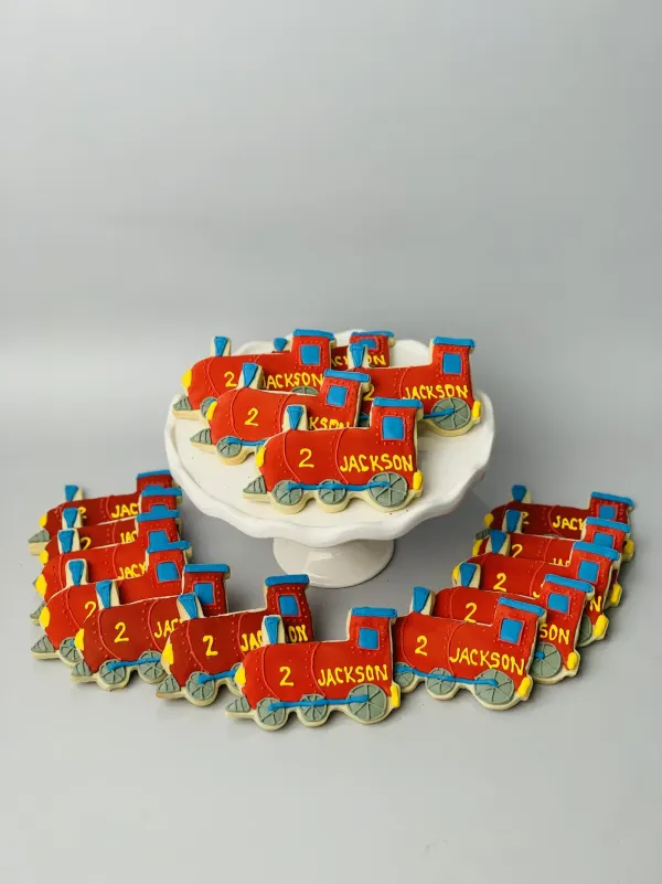 Red train engine sugar cookies piped with the number 2 and the name JACKSON in yellow