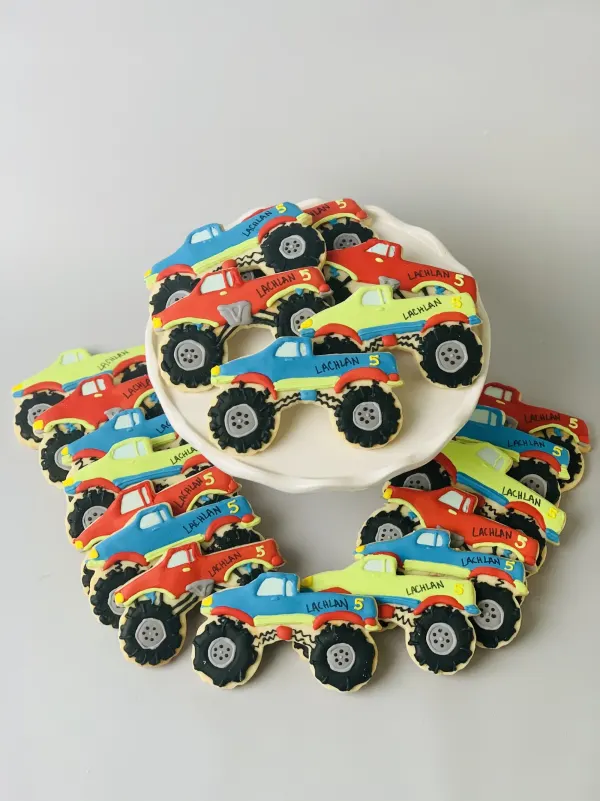Monster truck sugar cookies in red, blue and green iced with LACHLAN and the number 5