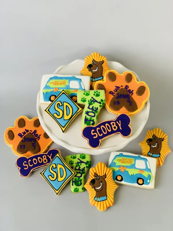 Scooby-Doo cookies with SCOOBY bone plaques, SD badges and a paw print reading Joey is 7