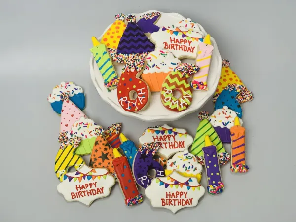 Birthday cookies with candles, party hats, cupcakes and number 6 cookies named RIYA and ROMAN