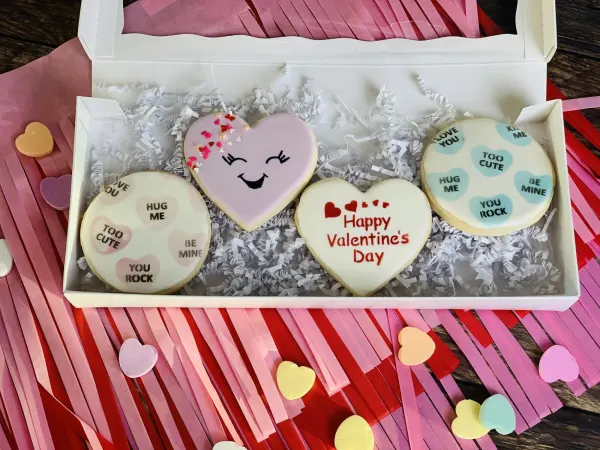 Boxed Valentine cookies with conversation-heart rounds and a smiling pink heart